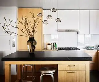 Isla de cocina de madera con cubierta negra y cocina detrás