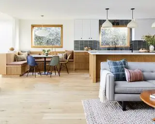 Una cocina con luces colgantes blancas sobre la isla de roble blanco y el área de desayuno.