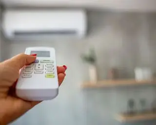 Camera da letto con scaffale donna che tiene il controller AC puntato verso l'unità AC sulla parete