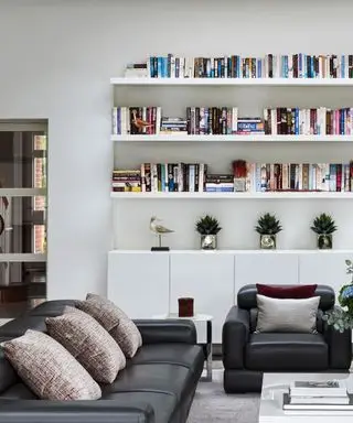 librerie in soggiorno bianco con poltrona e divano in pelle nera