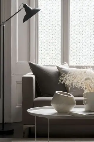 sala de estar con esquema neutro, sofá gris, mesa de café blanca, lámpara de pie negra, película para ventanas, jarrones de cerámica blanca