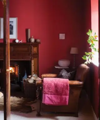 salon avec murs peints en rouge profond et canapé en cuir marron foncé