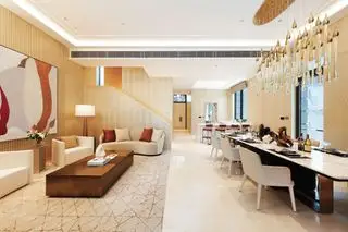 Sala de estar moderna em plano aberto com zona de jantar, área de sofá e tapete e paredes creme