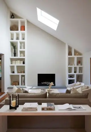 sala de estar em plano aberto em tons creme claros, lareira moderna, estantes embutidas e mesa de console