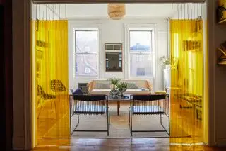 Um apartamento com sala de estar em Nova York com cortinas de plástico amarelas como divisórias