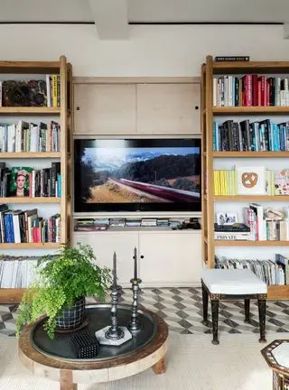 TV-stue med bokhylle bygget rundt sentral TV på kremvegg