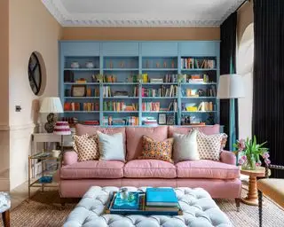 Soggiorno colorato con scaffalature blu su misura, divano con motivi rossi, pouf, tavolini,