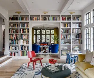 Soggiorno con una parete di librerie dal pavimento al soffitto come divisorio