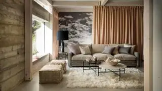 Pokój dzienny, czarno-biała sofa w kratkę, dywanik z alpaki ze zwierzęcego futra, poduszki podłogowe, panel ścienny ze zdjęciami alpejskich scen górskich