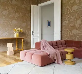 sala com papel de parede estampado bege, sofá coral, tapete creme