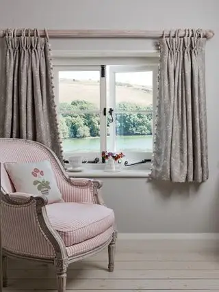 Rideaux cottage courts avec garniture dans une maison traditionnelle avec fauteuil rose