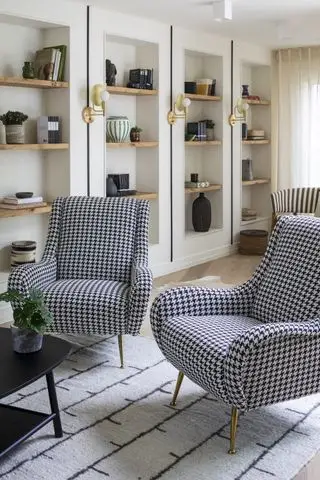 obývacia izba s viacerými výklenkami, kreslá houndstooth, vzorovaný koberec, nástenné svietidlá, konferenčný stolík
