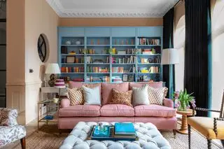 sala de estar com estante azul sob medida, sofá rosa e paredes creme