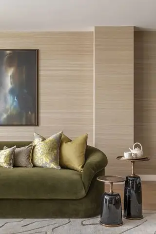 sala de estar neutra com paredes de madeira e sofá de veludo verde musgo com almofadas e mesas verdes