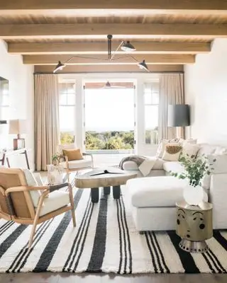 Idee feng shui per il soggiorno: tappeto a strisce bianche e nere, soffitto e mobili in legno con cuscini bianchi e pareti