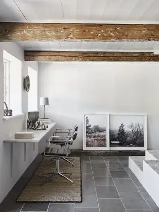 sala de estar con escritorio colgado en la pared y obras de arte apoyadas contra la pared