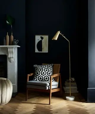 Schwarze Wohnzimmer-Anstrichideen mit einem Holzstuhl und einem grafischen Kissen.
