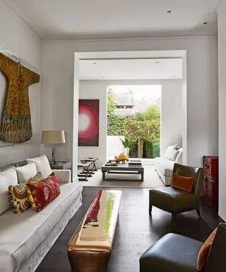 Ideen für weiße Wohnzimmerfarben mit roten Akzenten bei den Kissen und der Wandkunst.