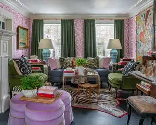 Ideias formais para salas de estar com papel de parede estampado rosa e branco, cortinas verdes, sofá azul, poltronas verdes e pufe lilás