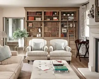 Ideias formais para salas de estar com poltronas tradicionais creme e estantes de madeira
