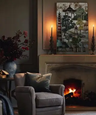 Gemütliches Wohnzimmer mit Kamin, mit Kunstwerken dekoriertem Kaminsims und Kerzen