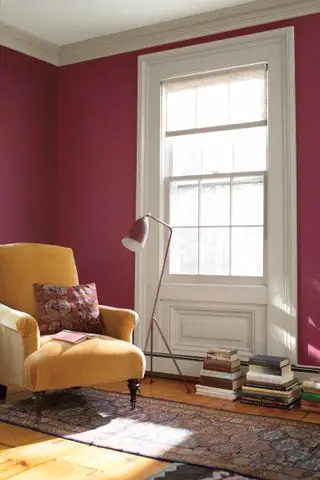Sala vermelha com parede vermelha, poltrona amarela, piso de madeira e tapete estampado