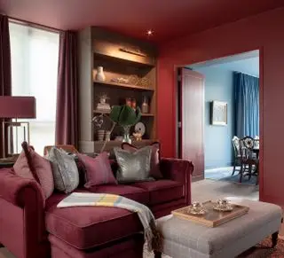 Sala vermelha com sofá vermelho, paredes e porta vermelhas e piso de madeira