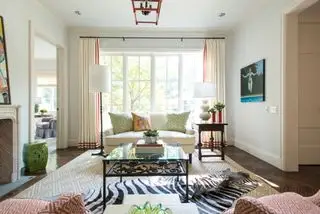 Sala de estar neutra com estofamento estampado vermelho, cortinas e vasos