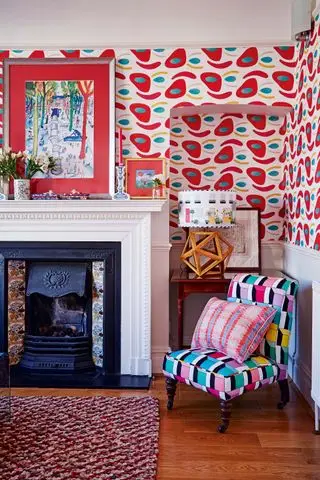 Sala com lareira, poltrona e papel de parede estampado