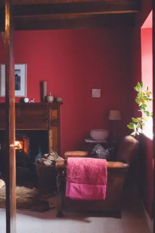 Sala com paredes vermelhas, poltrona de couro e lareira