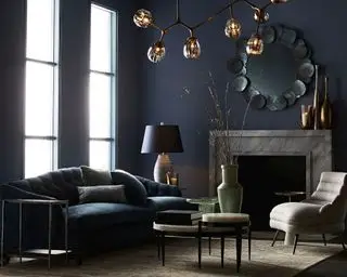 En mørkegrå Arteriors Shawnee stue med mørkegrå sofa, bordlampe og taklampe i metall.