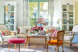 vakker stue med sofa og lenestoler og elegant blomsterutstilling på salongbord i midten