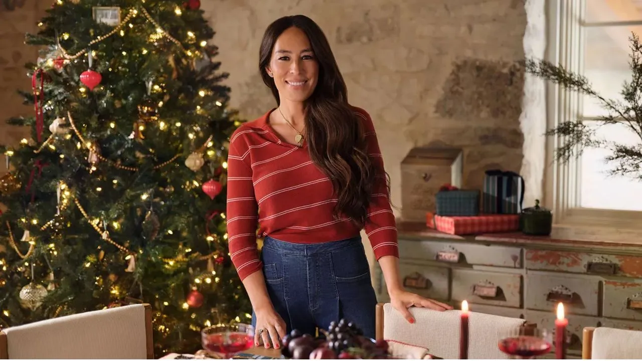 Joanna Gaines na sala de jantar com uma árvore de natal e gavetas antigas ao fundo' loading='lazy' title=