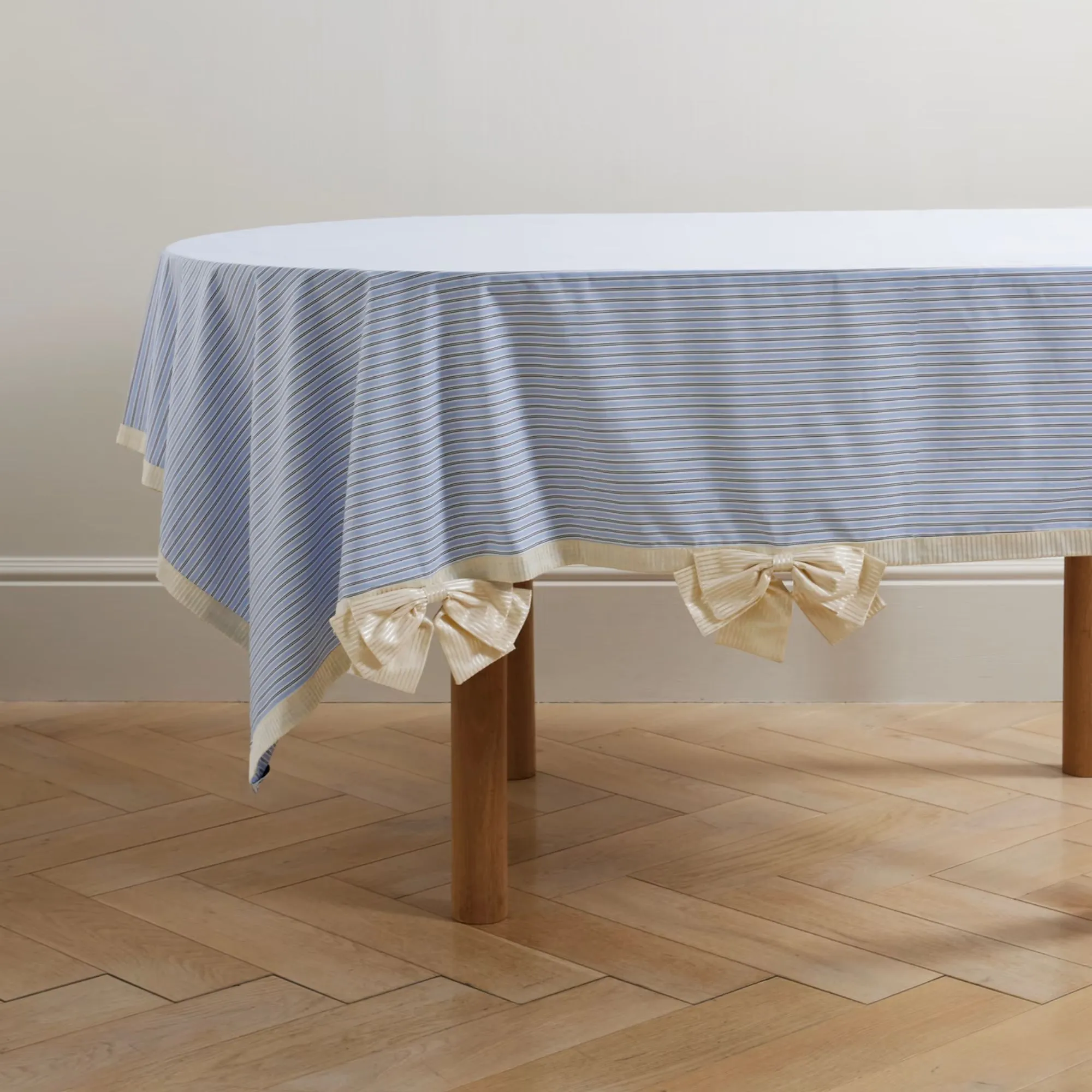 Mantel de rayas azules y blancas con ribetes blancos y lazos blancos.' loading='lazy' title=