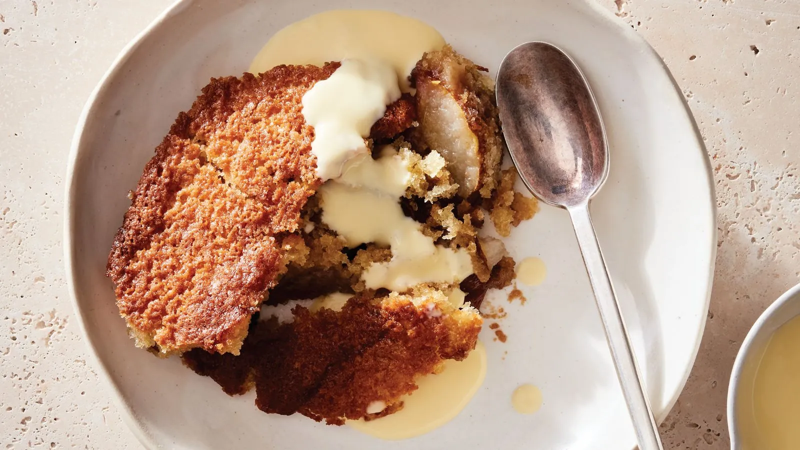 Hruška a karamelový švec v misce s creme anglais a lžičkou' loading='lazy' title=