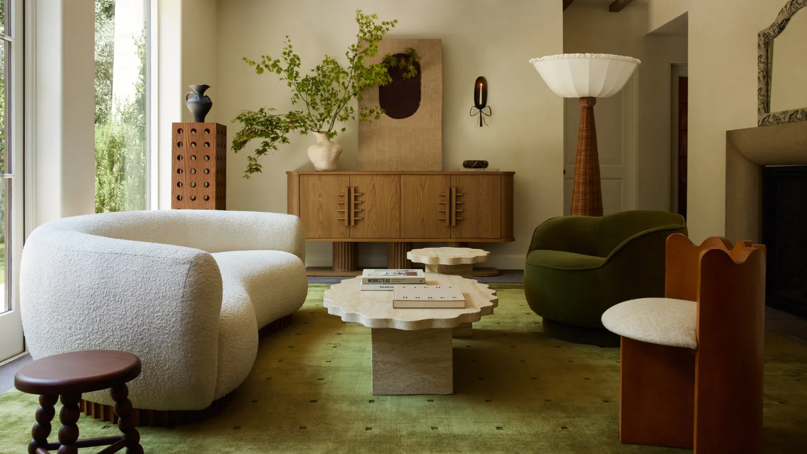 un salon chaleureux et accueillant avec un grand tapis vert un canapé bouclé blanc des chaises d'appoint dépareillées une table basse en marbre et un grand buffet en bois à l'arrière adjacent à un lampadaire en rotin' loading='lazy' title=