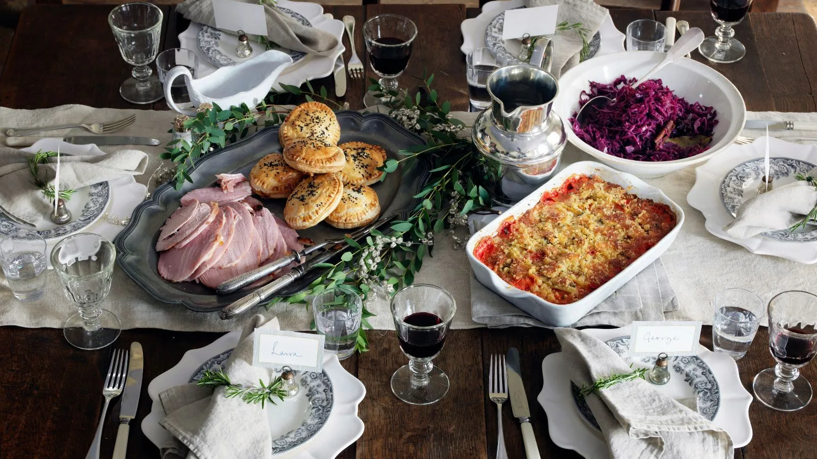 Vista aerea della cena autunnale con cavolo rosso prosciutto e casseruola con piastre bianche e un runner da tavolo bianca' loading='lazy' title=