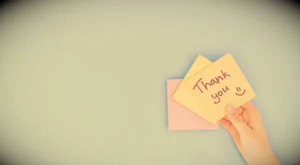 A hand holding a post-it that says: Thank you