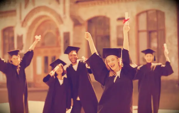 Happy students on graduation day celebrating outside their school.