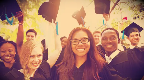 Happy graduates with their hats in the air on gradation day.