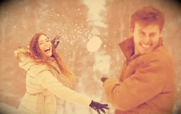 A couple having fun with a snowball fight.