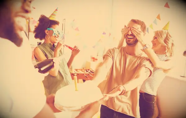 Friends presenting a man with a cake on his birthday.