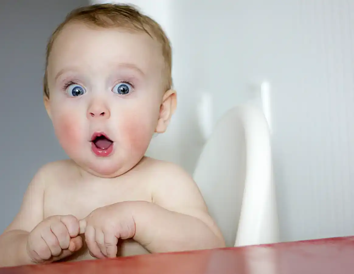 Surprised kid sitting at table stock photo