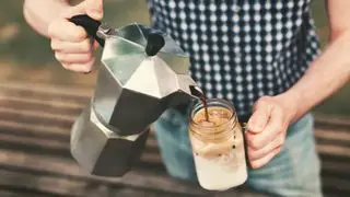 Una prensa francesa que vierte café sobre una jarra kilner para hacer café helado
