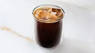 Un café helado negro sobre una encimera de mármol.