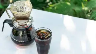 Una cafetera de goteo preparando café helado sobre una mesa