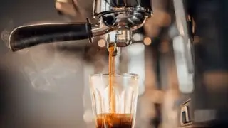 Un espresso en un vaso bajo el portafiltro de una máquina de espresso