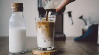 un café helado frente a una cafetera con leche al lado
