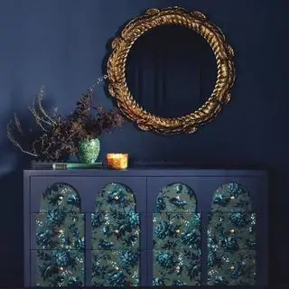 Anthropologie House of Hackney Kommode med seks skuffer mod en flådevæg med et guldspejl,