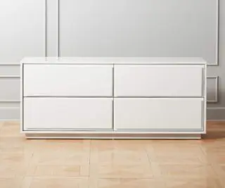 Hvid CB2 kommode mod en grå væg.